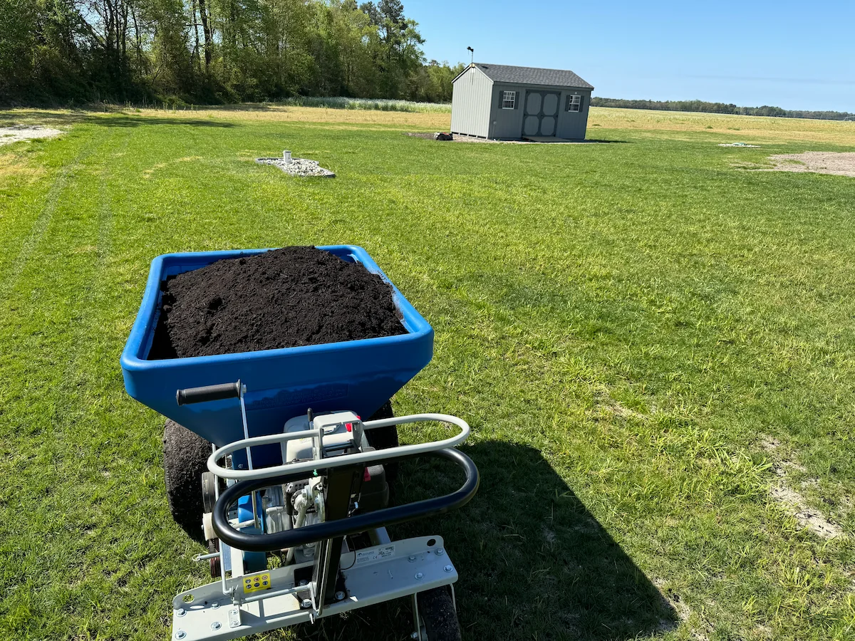 Compost spreader applying top dressing to lawn for Lawn Renovations compost top dressing by Harvest Turf Care in Sussex County DE