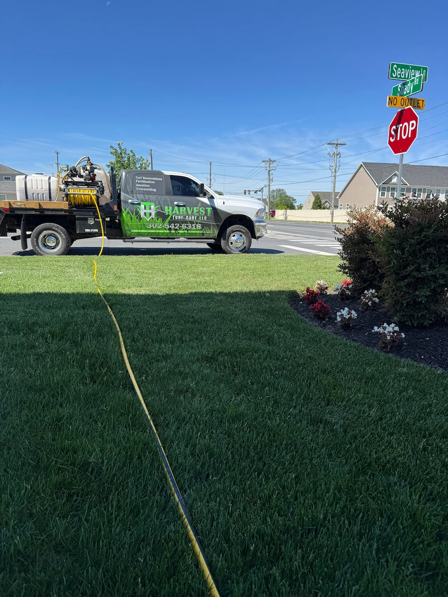 Harvest Turf Care truck spraying lawn near residential intersection